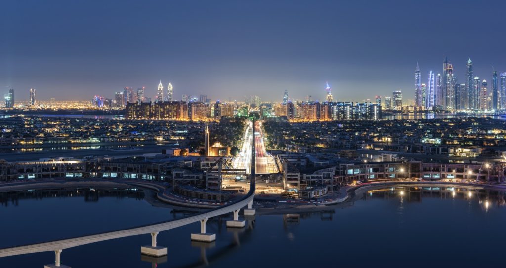 Cityscape of Dubai, United Arab Emirates at dusk, with illuminated skyscrapers in the distance and